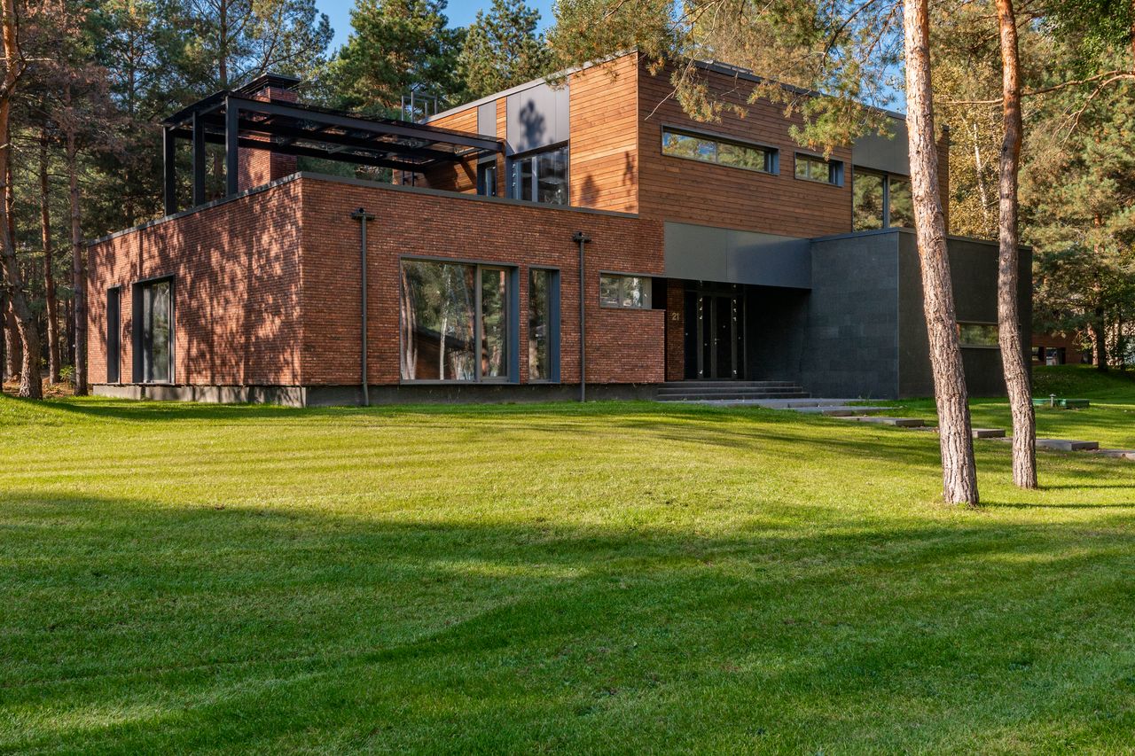 Contemporary house with large windows surrounded by lush greenery and trees.